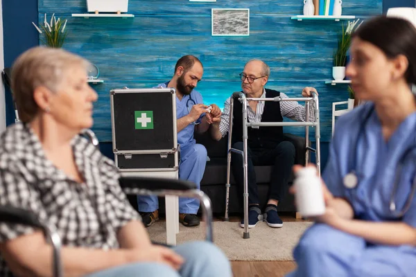 Socialassistent diskuterar vårdmedicin med äldre pensionärer med funktionshinder — Stockfoto