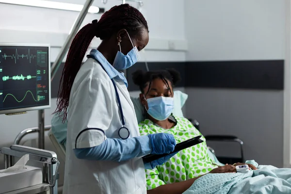 Medic van Afrikaanse etniciteit die zieke patiënt in kliniek helpt — Stockfoto