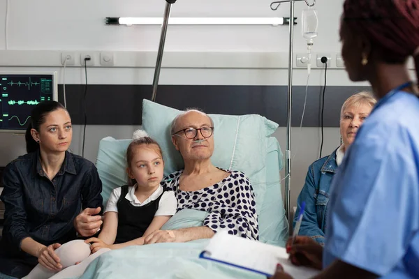 Afrikanisch-amerikanische Krankenschwester diskutiert Krankenbehandlung mit älterem älteren Mann — Stockfoto
