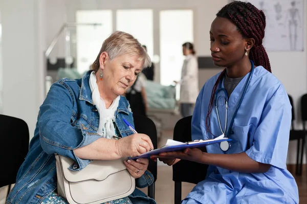 노인 환자에게 병 치료를 설명하는 아프리카 계 미국인 간호사 — 스톡 사진
