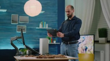 Adam mimar elinde tablet ve yapı modeli tutuyor