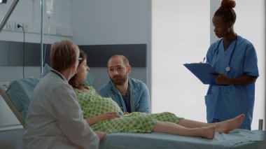 Doktor ve Afrikalı Amerikalı hemşire çocuk bekleyen kadınlara danışmanlık yapıyor.