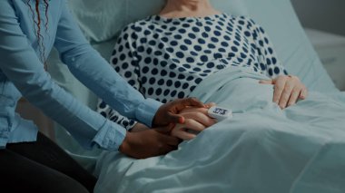 Afro-Amerikalı kadın hastane koğuşundaki hasta hastayı ziyaret ediyor.