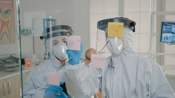 Ortodontistas em ternos ppe fazendo diagrama com notas pegajosas — Fotografia de Stock