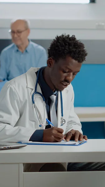 Αφροαμερικανός γιατρός γράφει τσεκ-απ στο σημειωματάριο — Φωτογραφία Αρχείου