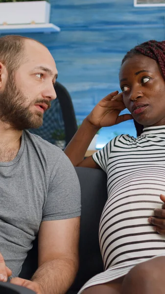 Interracial couple expecting child and bonding on couch — Stock Photo, Image