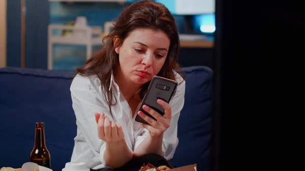 Blanke vrouw bijten plak pizza en het houden van smartphone — Stockfoto