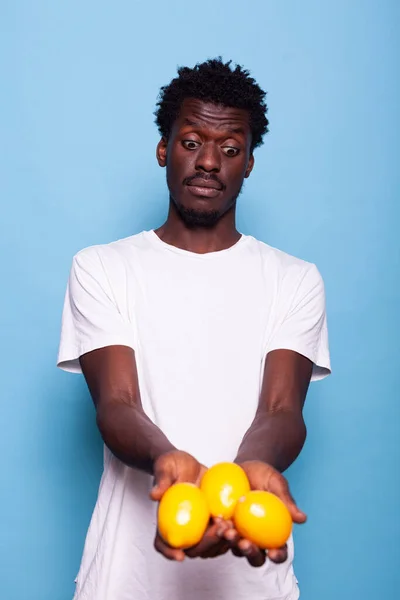 Afro-américain adulte tenant des citrons frais et posant — Photo