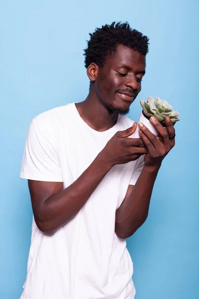 Afrikansk amerikansk man ler och tittar på kruka med växt — Stockfoto