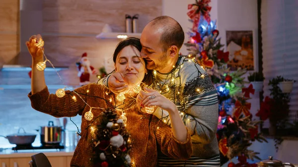 Couple festif noué dans une chaîne de lumières de Noël — Photo