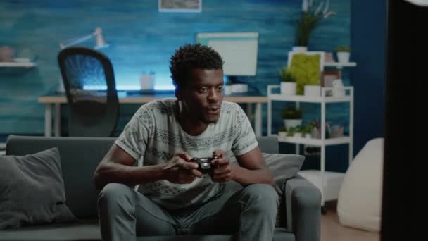 Щасливий чоловік грає у відеоігри з контролером на консолі — стокове відео