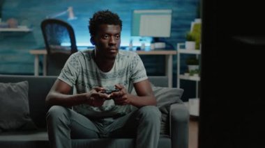 Oyun kumandası ve TV konsolu ile oyun oynayan kişi