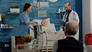 Doktor ve hemşire hastane yatağında hasta kontrolü yapıyorlar.