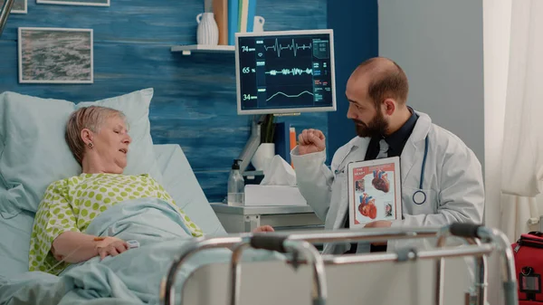 Arts toont cardiovasculair beeld op tablet aan zieke patiënt — Stockfoto