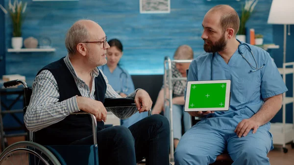 Uomo infermiera e vecchio paziente guardando schermo verde su tablet — Foto Stock