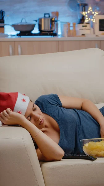 Ospalá žena v Santa klobouku a odpočívá na gauči — Stock fotografie
