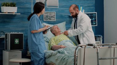 Doktor hasta üzerinde steteskop kullanarak kalp atışı kontrolü yapıyor.