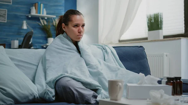 Mujer enferma con gripe estacional temblando en manta en casa —  Fotos de Stock