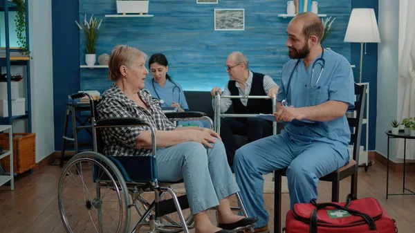 요양원에 신체 장애가 있는 연로 한 여자 와상의 하는 남자 간호사 — 스톡 사진
