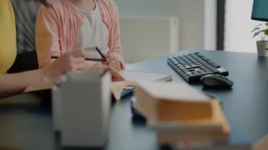 Not defterine ödev yazan küçük bir çocuk ve yardımcı annesi.