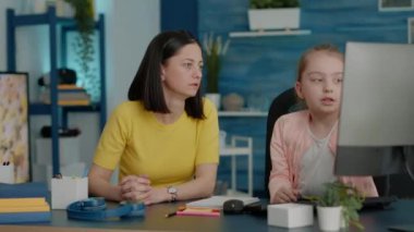 Anne, bilgisayar derslerinde genç öğrencilere yardım ediyor.