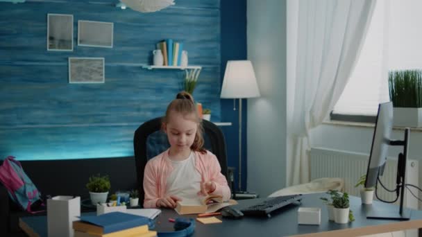 Caucasian girl reading book at desk for primary school work — Stock Video
