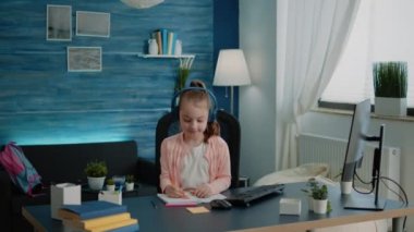 Ders kitabına göre çizen ve bilgisayar kullanan küçük çocuk