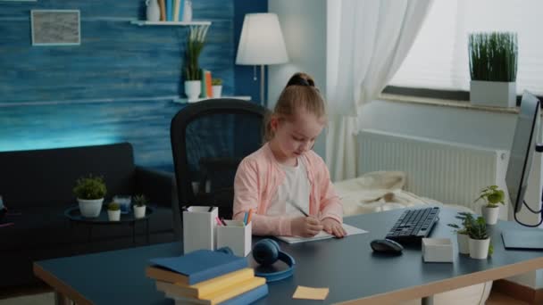 Schoolgirl using colorful pencils to draw on notebook at desk — Stock Video