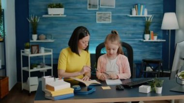 Uzaktan eğitim için annesiyle ödev yapan küçük bir çocuk.