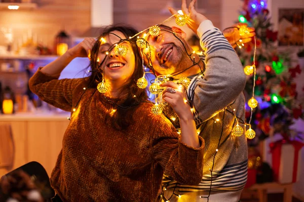 Couple drôle caughting dans la lumière de l'arbre de Noël pendant la période de Noël — Photo
