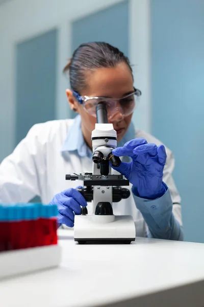 Mujer bióloga analizando muestras de sangre con microscopio —  Fotos de Stock