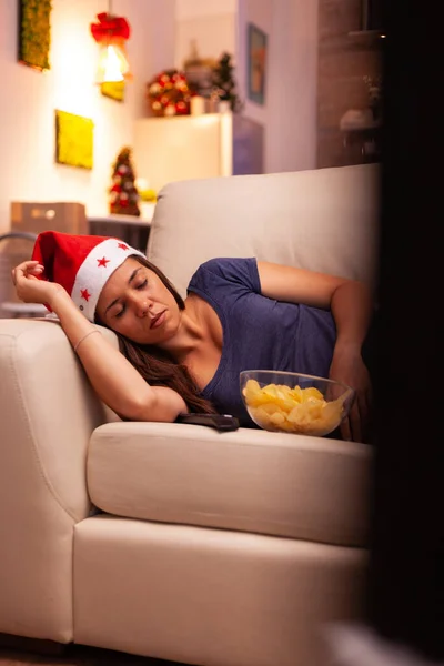 Vrouw met santa hoed slapen op bank na het kijken naar de winter entertainment film — Stockfoto