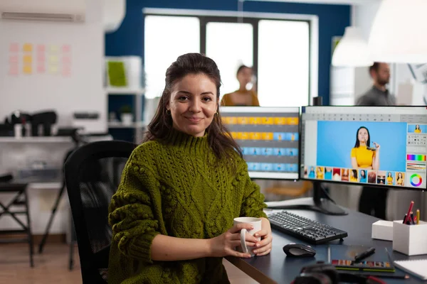 Woman retoucher looking at camera smiling sitting in creative design media agency