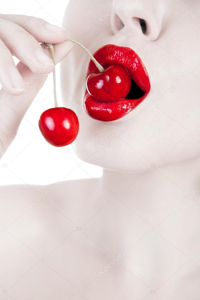 Mouth with red lips biting cherry 