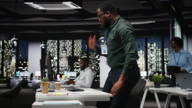 Siyah genel müdür gecenin geç saatlerinde karanlık bir ofiste karmaşık bir sorun düşünüyor. İş yerindeki seçeneklere odaklanıyor. Dikkatli çıkarımlarla mantıksal çözümü yansıtıyor. Kamera A.