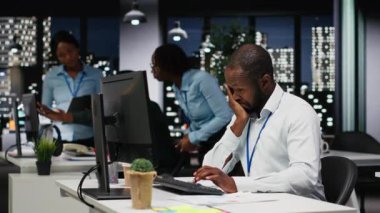 Yorgunluk ve tükenmişlik nedeniyle siyah işadamı, yorgun olduğunu gösteren belirtiler göstererek ellerini dinlendiriyor. Kariyer zorluğu çeken bir işçi ve sürekli uykusuzluk çeken bir işçi. Kamera B.