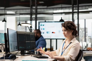 Kadın ofis çalışanı, çok uluslu bir şirket alanındaki iş kaynakları ve performans ölçümlerini incelemek için dijital teknoloji kullanır. Verimlilik için veri içgörüleri kaldırılıyor.