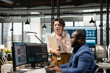 Aylık raporları tamamlamada birbirlerine danışan çok ırklı çalışma ekibi, KPI 'nin iş verimliliği hakkındaki veri içgörülerini gözden geçiriyor. Başarı için çalışanlar arasındaki işbirliği.