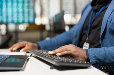 Siyahi erkek işçiye yakın çekim stratejik bir zihniyet gösteriyor ve iş verilerini performans ölçüsüyle analiz ediyor. Çalışma yerindeki bilgisayardaki raporları yönetiyor. Büyümeyi garantile.