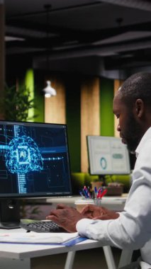 Dikey Video Ofisi çalışanı aylık veri raporlarını AI analitik platformu ile kontrol ediyor, nöral ağ algoritmalarını gözden geçiriyor ve iş verimliliği için otomasyon yapıyor. IT şirketinin temsilcisi