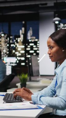 Dikey Video Kadın Profesyonel Araştırma ve belgelendirme bilgileri, karanlık bir ofiste işletme girişimi için güncellemeler raporlar. Bilgisayarda finans hedefleri ve proje geliştirme