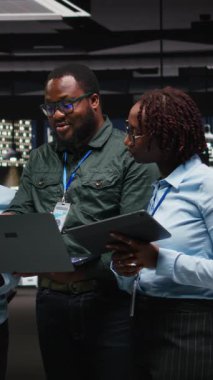 Ortaklar grubunun dikey video portresi gece geç saatlerde cihazlarda veri numaralarını gözden geçiriyor, strateji planlaması ve yeni hedefler için metrik analiz ile iş çözümleri geliştiriyor. Kamera.