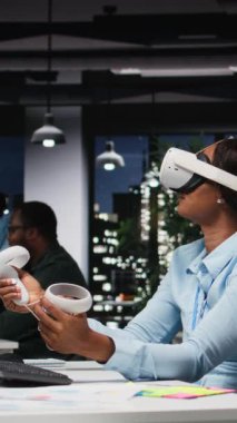 Dikey Afrikalı Amerikalı kadın yapay zeka aygıtını karanlık ofiste kullanıyordu. Projeksiyonların doğruluğunu kontrol etmek ve analiz etmek için şirketin çalışma alanında VR gözlükleriyle fazla mesai yapıyordu.