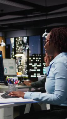 Dikey Video Siyah kadın uzman KPI raporlarını bilgisayarda yapay zeka araçlarıyla inceleyerek makine öğrenimi için yapay zeka ağlarıyla çalışıyor. Yenilik ve optimizasyon vurgulanıyor