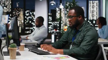 Afrika kökenli Amerikalı danışman gecenin geç saatlerinde bir not defterinden bilgi alıyor ve işletme yönetiminin finans raporlarından özetler hazırlıyor. Not almak hedef ayarlarını destekler. Kamera B.