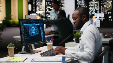 Siyahi adam analist veri madenciliği ve optimizasyonu için yapay zeka ağları kullanıyor. Otomasyon araçlarıyla çok uluslu bir şirkette çalışıyor. Başarı için yapay zeka dijital araçları. Kamera B.