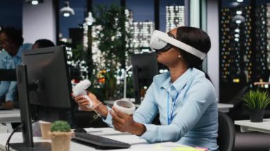 Afrika kökenli Amerikalı bir kadın AI cihazını karanlık ofiste sanal gerçeklikle kullanıyor. Projeksiyonların doğruluğunu kontrol etmek ve analiz etmek için şirketin çalışma alanında VR gözlükleriyle fazla mesai yapıyor. Kamera B.