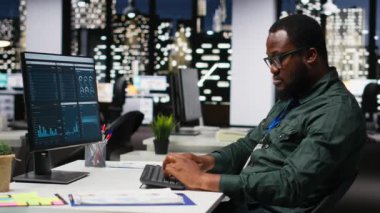 İş yönetimi için veri ve teknoloji kullanan erkek ofis çalışanı, raporlar oluşturmak ve verimliliği artırmak için monitördeki beyan grafiklerini gözden geçiriyor, hedeflere ulaşımı geliştiriyor. Vizyon. Kamera B.