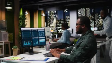 Yönetici, gece geç saatlerde bir bilgisayarda finansal veri bilgileriyle ilgilenerek, yenilikçi çözümler geliştiriyor ve proje hedeflerini şirket hedeflerine göre hizalıyor. Şirket ortamı. Kamera A.