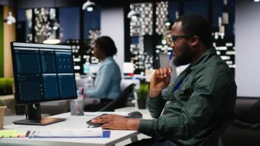 KPI ölçümlerini monitörde ve masaüstünde inceleyen ofis çalışanı, hedeflere ve başarıya ulaşmak için bir vizyon ve iş stratejisi oluşturmaktadır. Mesai sonrası profesyonel zihniyet. Kamera B.